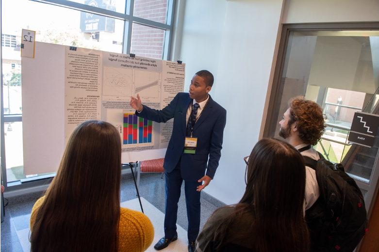 Forensics (Biological Sciences) major Jordan Cole received a 2022 Drapeau Summer 研究 Grant to study the effects of algae and fungi on wood decay under the mentorship of Biological Sciences professor, Dr. 凯文期. Here he is shown explaining his DCUR-funded research project to UGS 2023 attendees. 